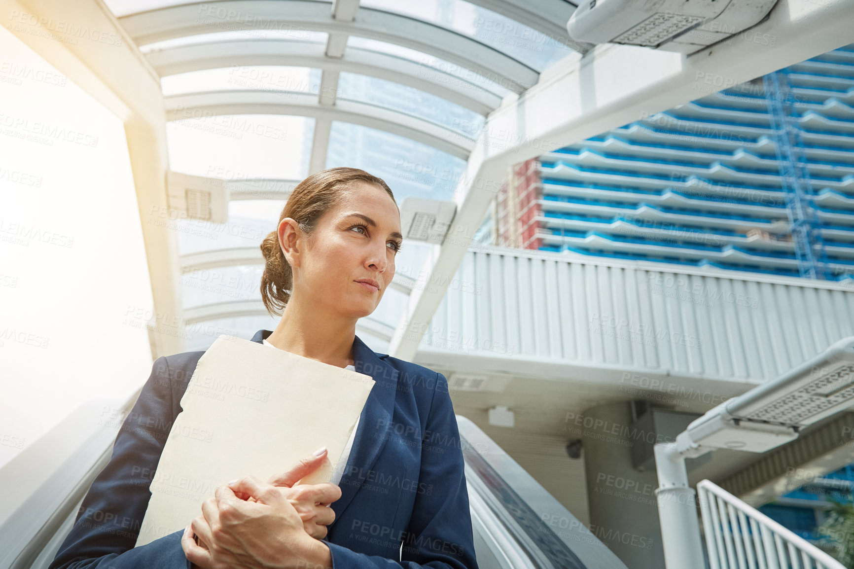 Buy stock photo Shot of a young businesswoman holding paperwork while on the way to the office