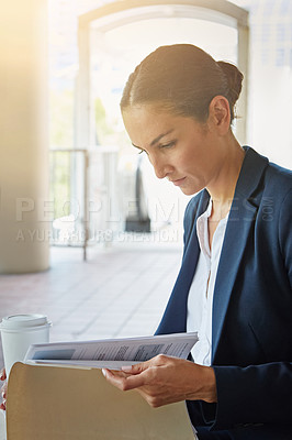 Buy stock photo Shot of a businesswoman reading paperwork while taking a break from the office