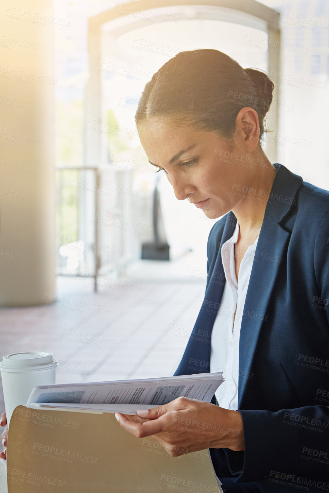 Buy stock photo Shot of a businesswoman reading paperwork while taking a break from the office