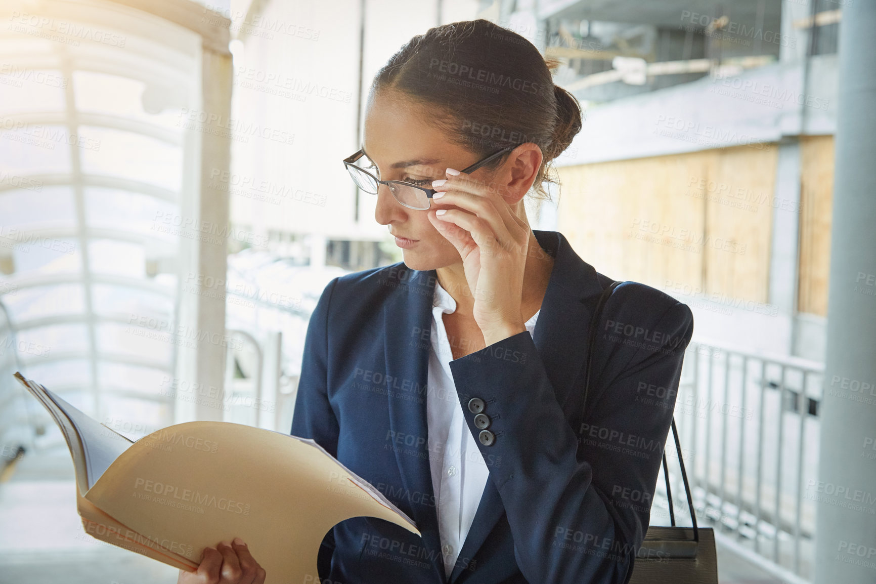 Buy stock photo Shot of a young businesswoman reading paperwork on her way to the office