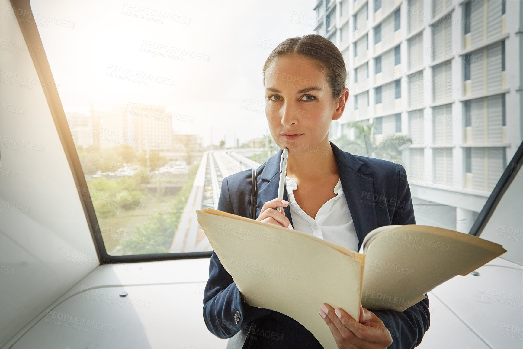 Buy stock photo Shot of a young businesswoman reading paperwork on her way to the office