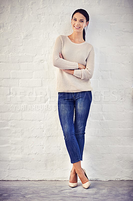 Buy stock photo Shot of a casually dressed young woman standing against a brick wall