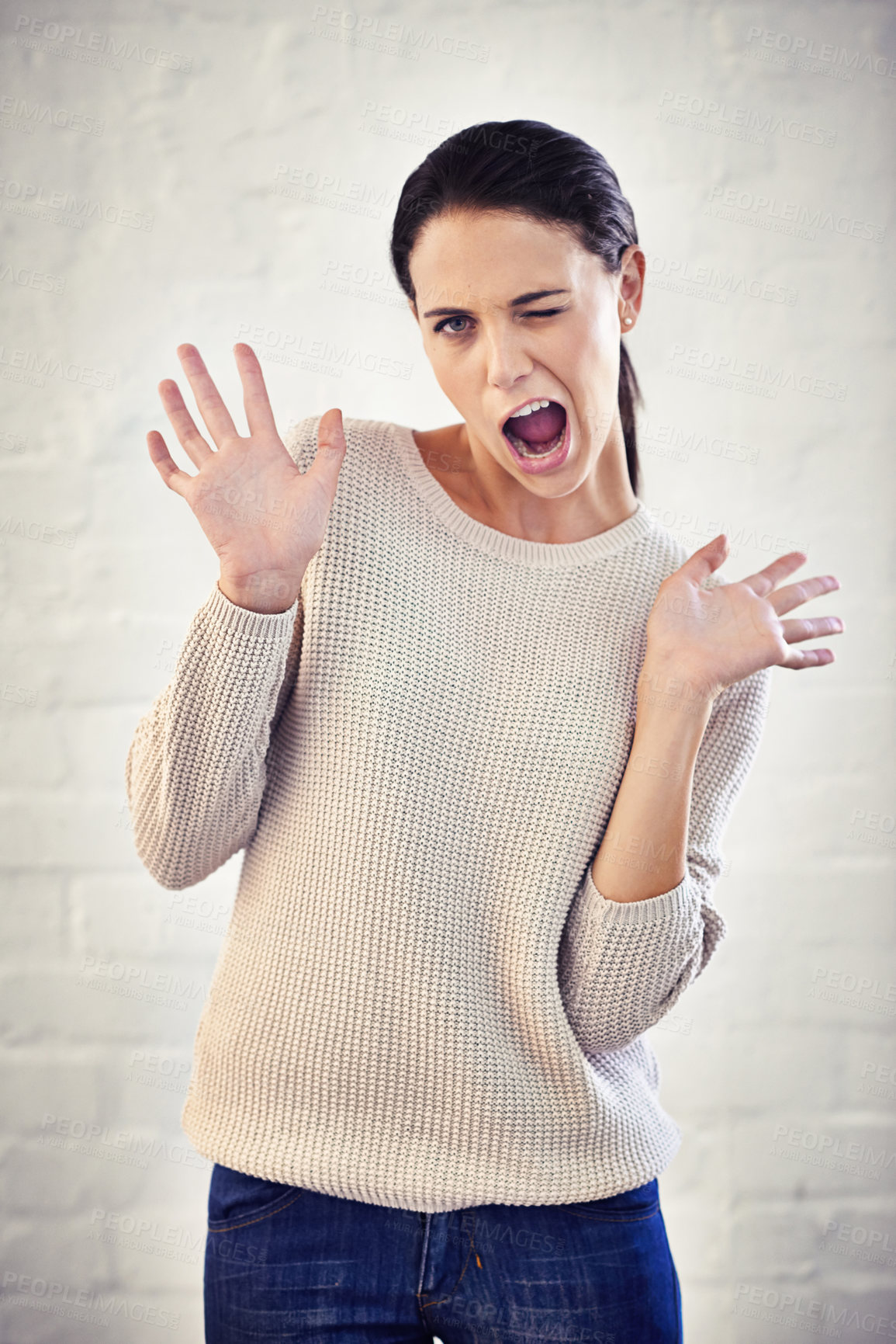 Buy stock photo Shot of a young woman with her hands in the air looking surprised