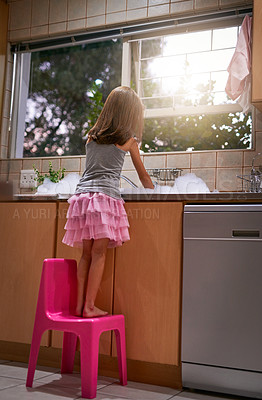 Buy stock photo Girl, chair and washing dishes in kitchen, chore and helping to clean for hygiene or disinfect dirt. Female person, back and water splash or bubbles for bacteria prevention, wet and care for germs