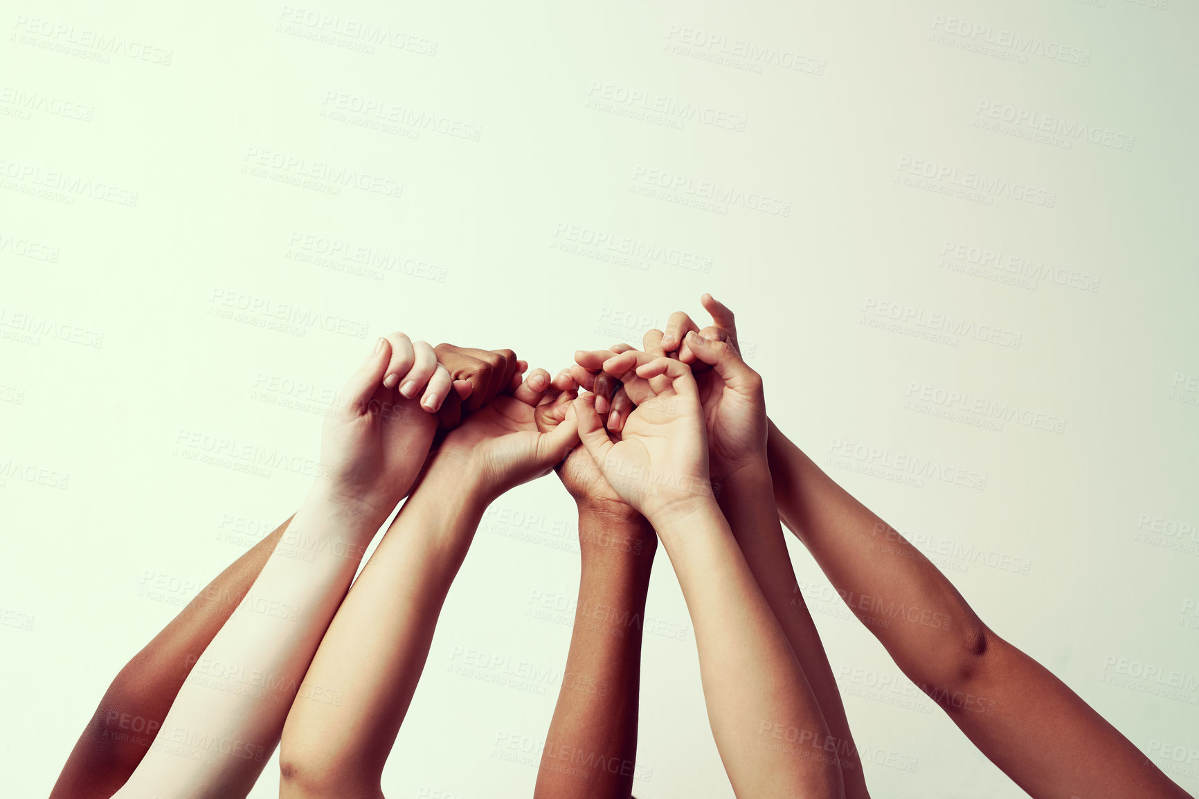 Buy stock photo Cropped shot of a group of people holding each others' thumbs with their hands raised
