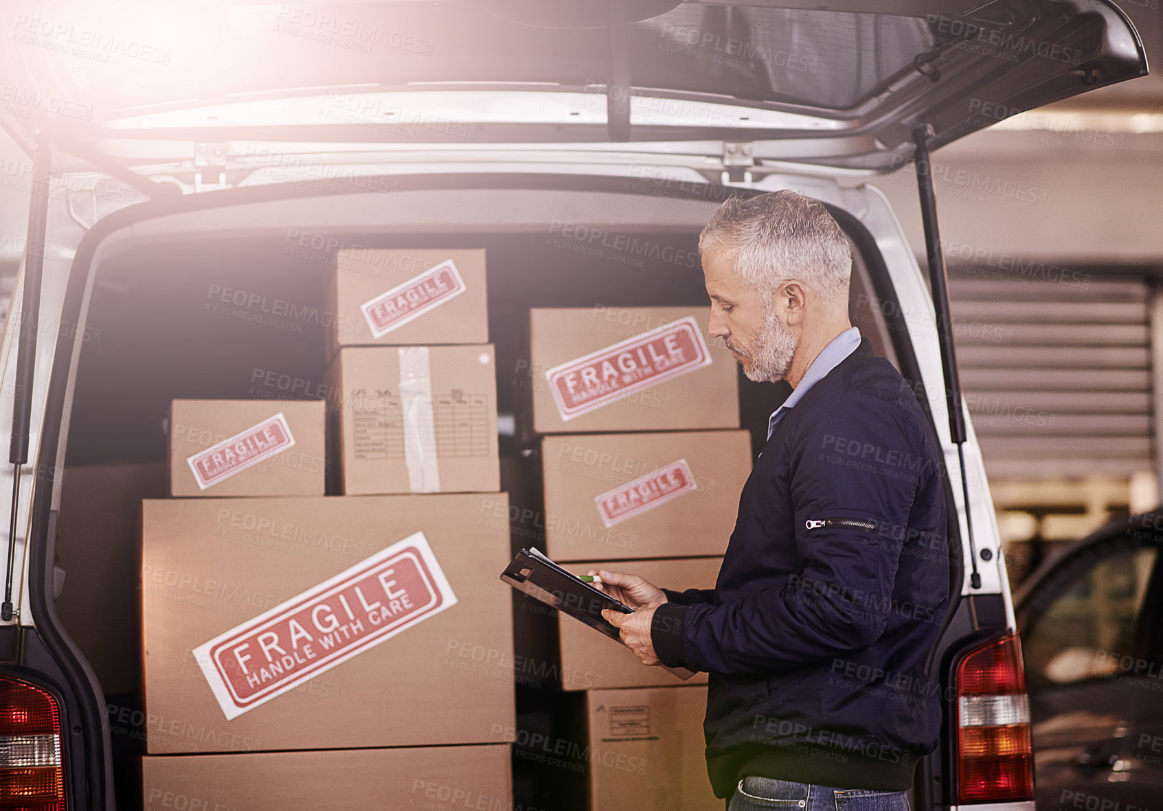 Buy stock photo Shot of a mature delivery man standing next to a van packed with boxes