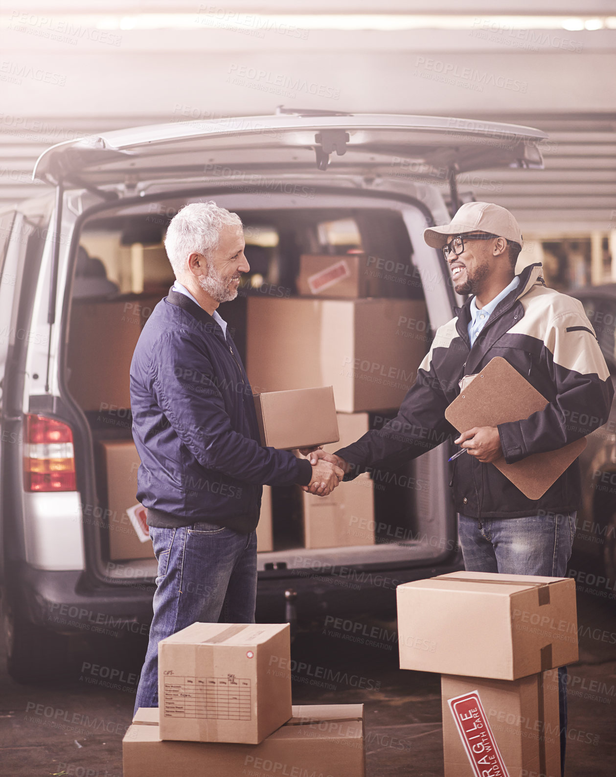 Buy stock photo Shot of two delivery men shaking hands next to a van filled with boxes
