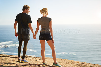 Buy stock photo Shot of a young couple looking at the view from the top of a mountain
