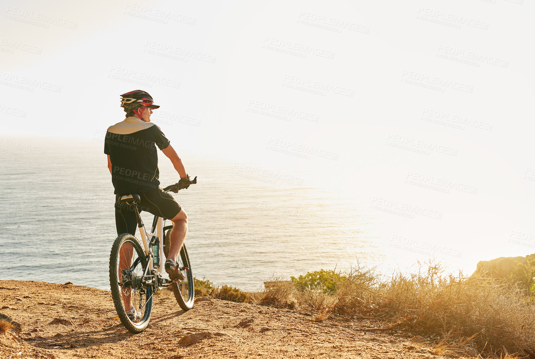 Buy stock photo Shot of a man admiring the view from a hilltop while out on a bike ride