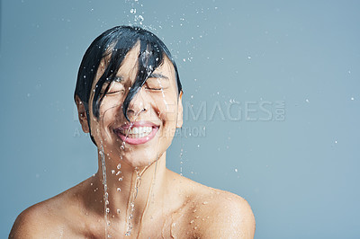 Buy stock photo Shot of a young woman having a refreshing shower against a blue background