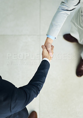 Buy stock photo High angle shot of two unidentifiable businessmen shaking hands in the office