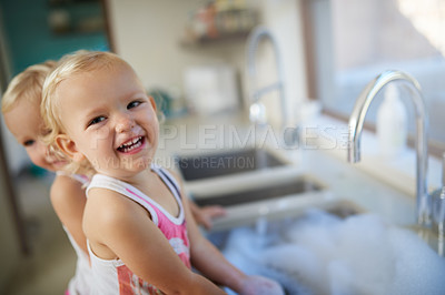 Buy stock photo Happy children, portrait and washing dishes with water in kitchen for cleaning, chores or housekeeping at home. Little girl or siblings with smile for learning, development or responsibility at house
