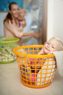 Buy stock photo Happy baby, portrait and relax with mom in laundry basket for fun childhood, game or chore day at home. Young little girl with smile in bucket while mother washing clothing in machine for hygiene
