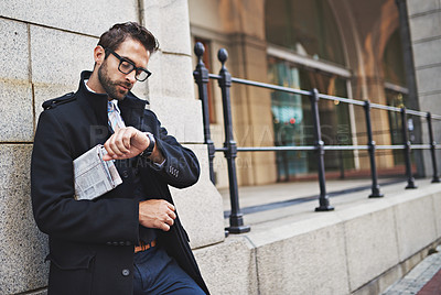 Buy stock photo Shot of a stylish young businessman checking the time while out in the city