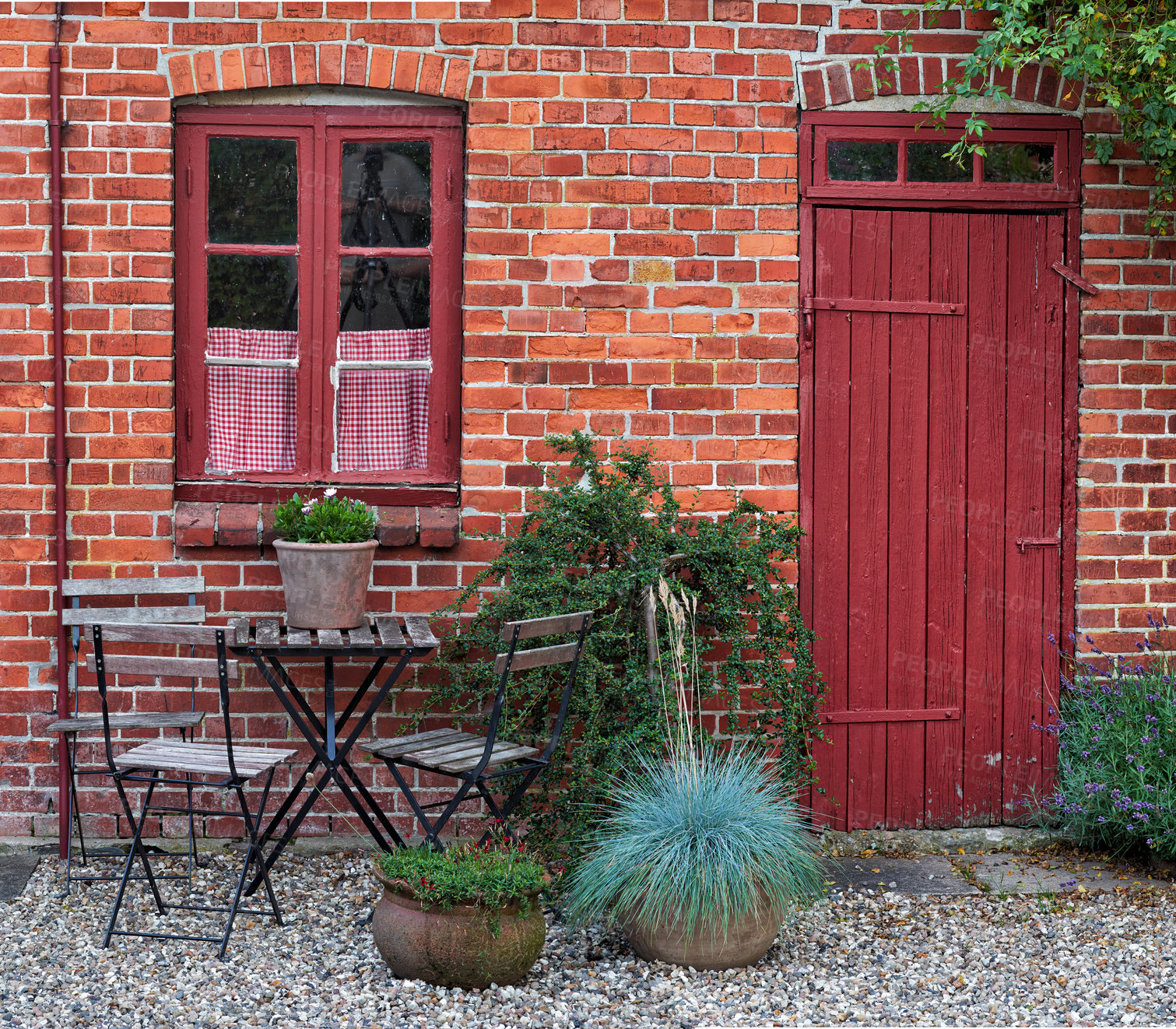 Buy stock photo An entrance view of a house with vintage chairs and a table. The brick facade of the old apartment with a window and a door, with plants. Red brick wall. Open space near the entrance of the house.