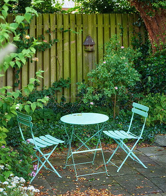 Buy stock photo Garden chairs and table in a relaxing, serene, peaceful, lush and private home backyard in summer. Green metal patio furniture seating in an empty and tranquil courtyard with fresh flowers and plants