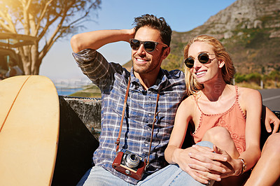 Buy stock photo Shot of a young couple relaxing on the back of a pickup truck while on a road trip