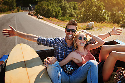 Buy stock photo Shot of a young couple relaxing on the back of a pickup truck while on a road trip