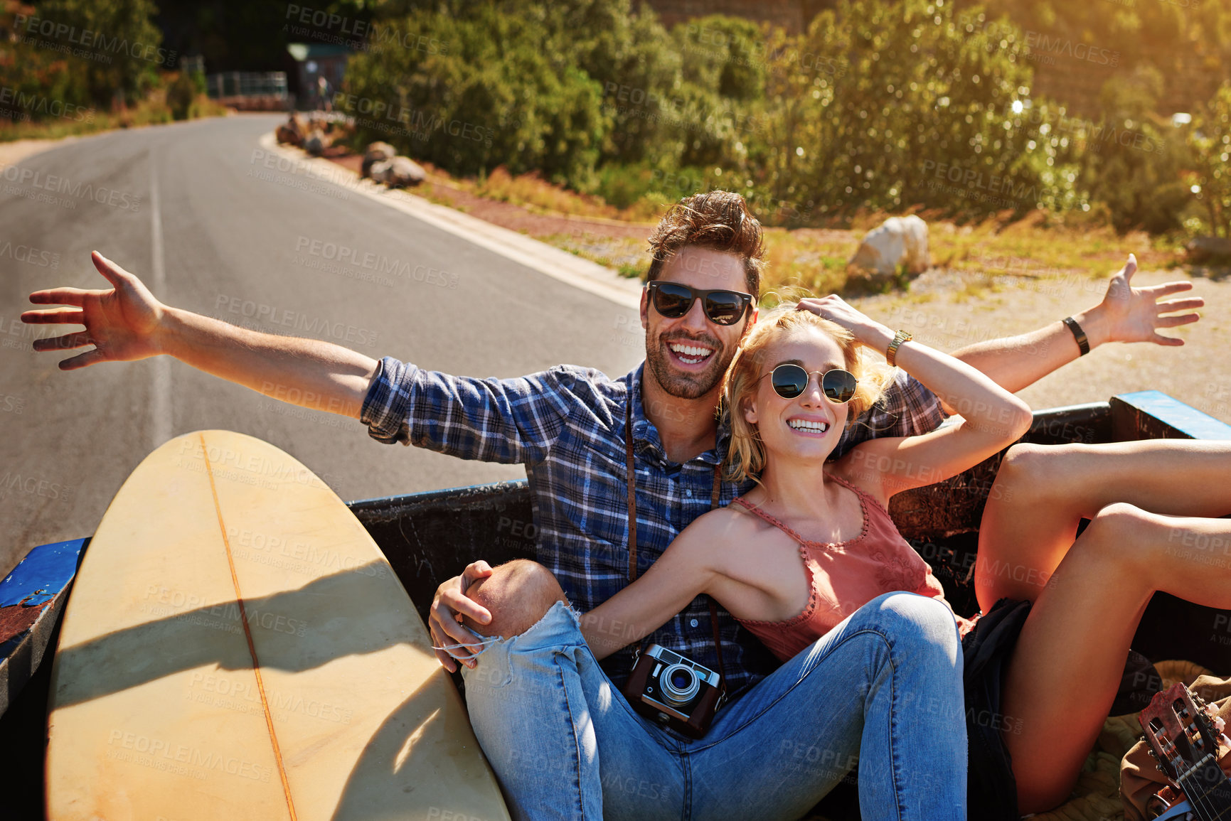 Buy stock photo Shot of a young couple relaxing on the back of a pickup truck while on a road trip