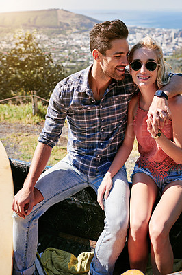 Buy stock photo Shot of a young couple relaxing on the back of a pickup truck while on a road trip