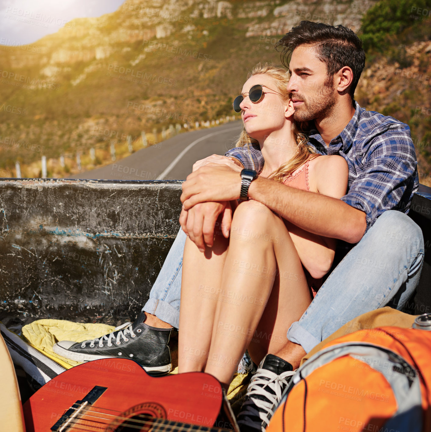 Buy stock photo Shot of a young couple relaxing on the back of a pickup truck while on a road trip