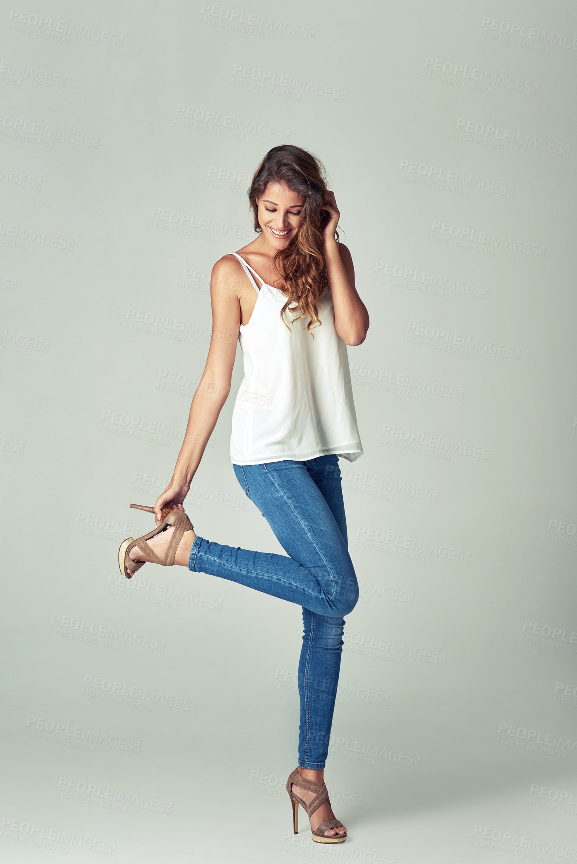 Buy stock photo Studio shot of a beautiful young woman getting undressed against a gray background