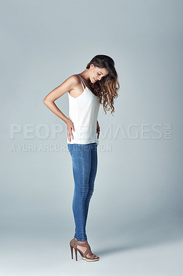 Buy stock photo Studio shot of a beautiful young woman trying on an outfit against a gray background