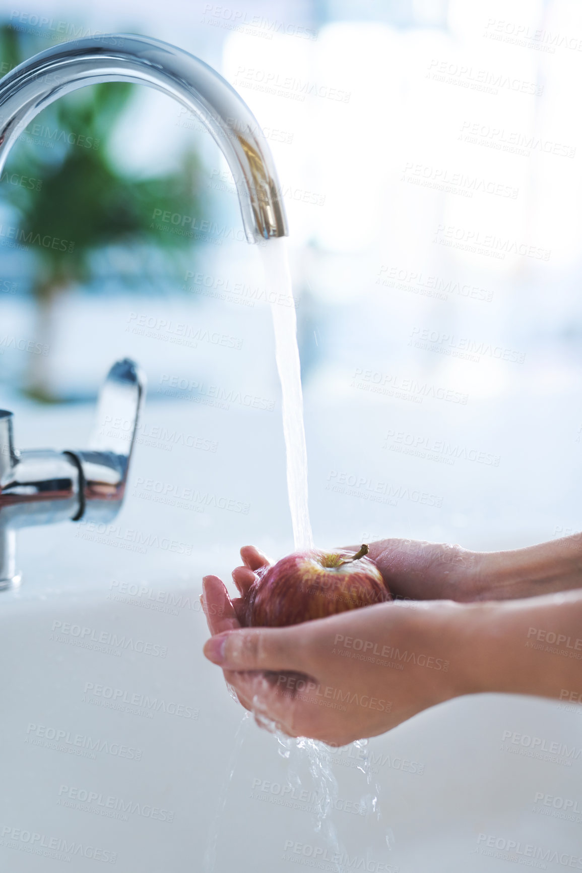 Buy stock photo Shot of a person washing an apple at a tap