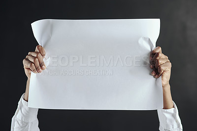 Buy stock photo Shot of hands holding up a blank page against a dark background