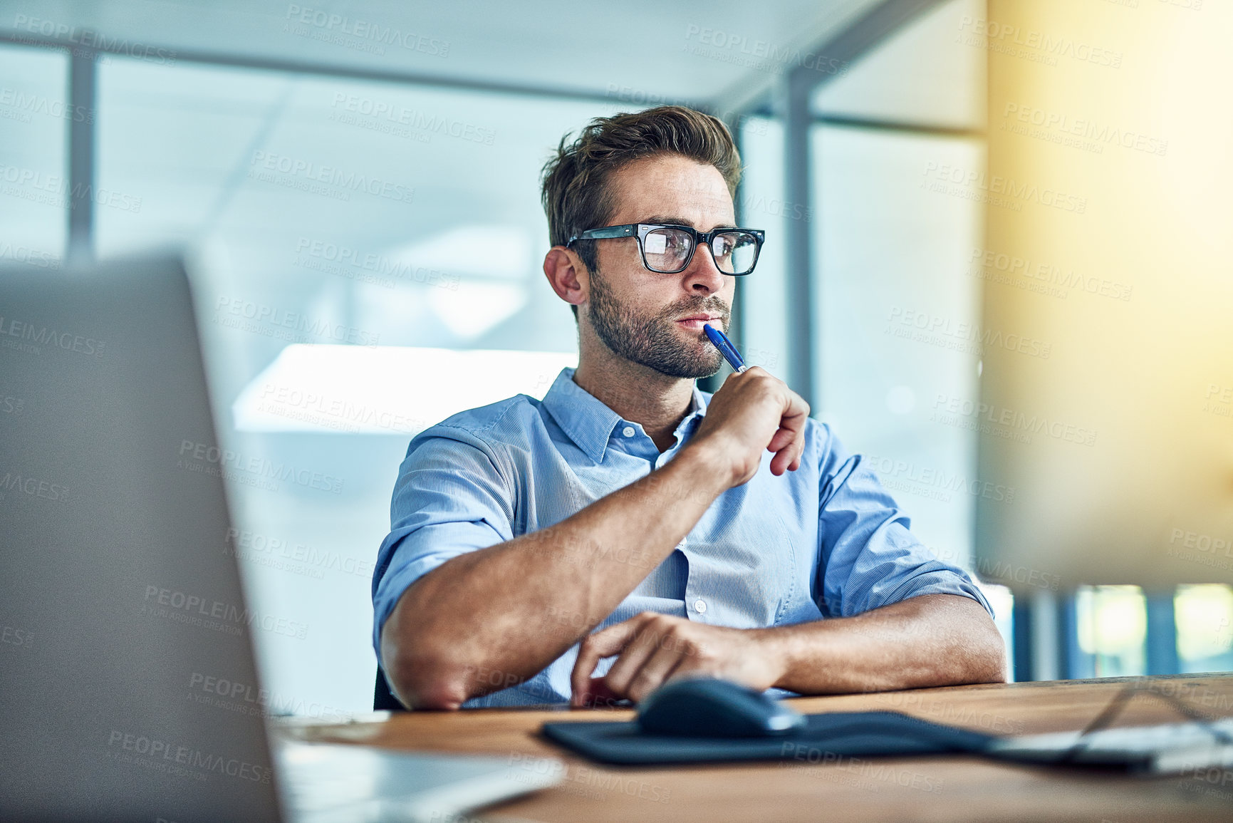 Buy stock photo Shot of a young businessman working on a computer in an office