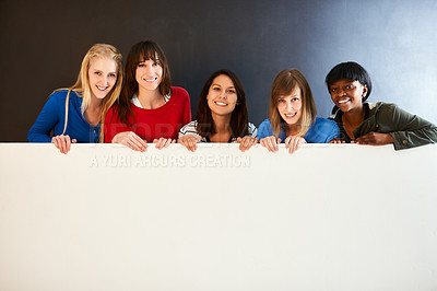 Buy stock photo Shot of a group of women holding a blank sign against a dark background