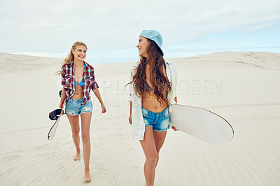 Buy stock photo Shot of two young friends sand boarding in the desert