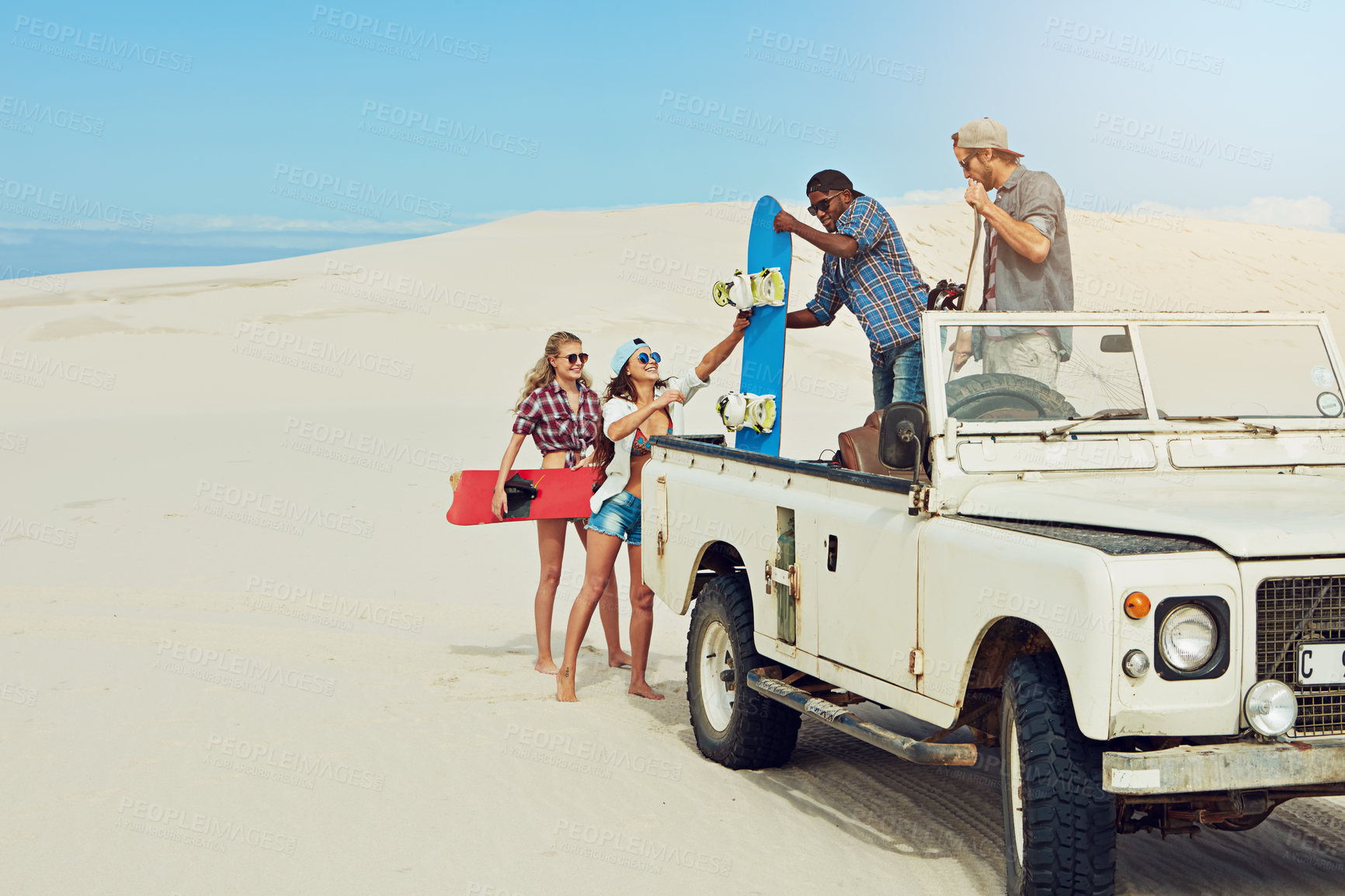 Buy stock photo Shot of a group of young friends going on a sand boarding road trip in the desert