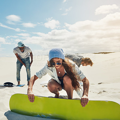 Buy stock photo Shot of young people sandboarding in the desert