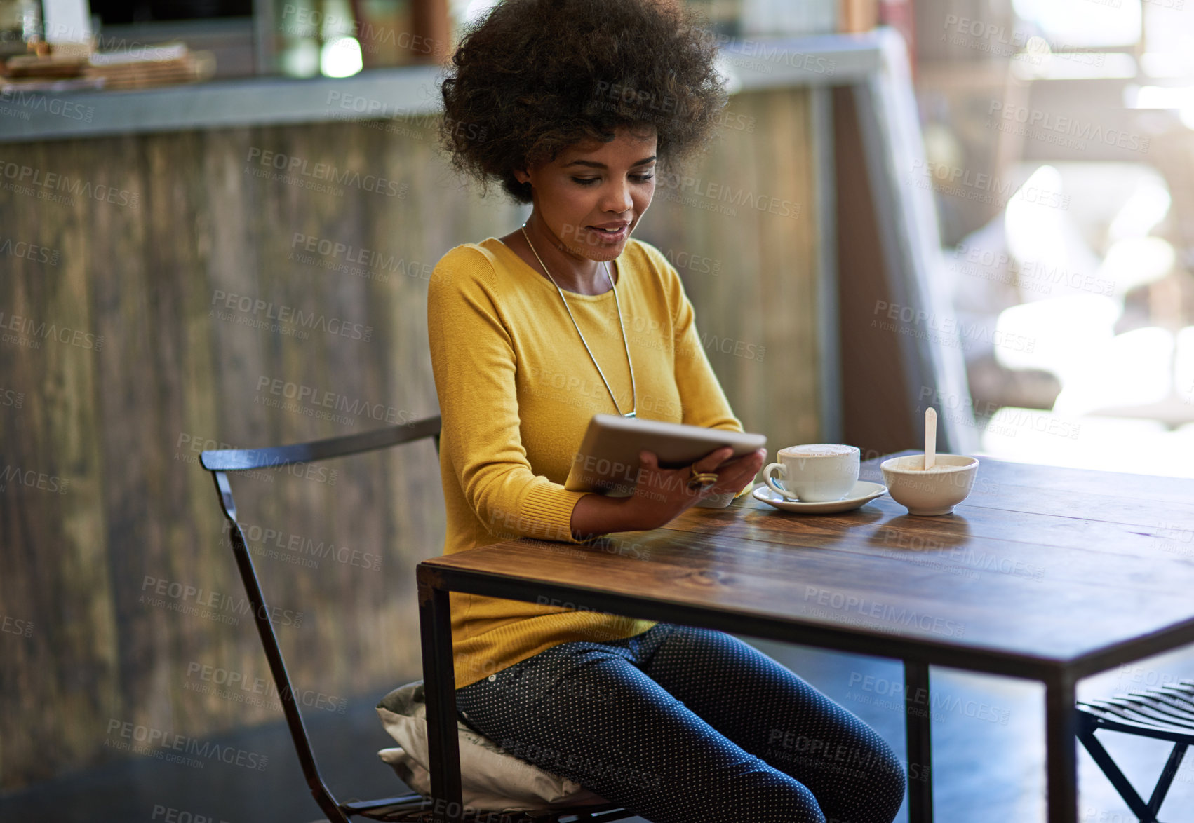 Buy stock photo Shot of a young woman using a digital tablet in a cafe