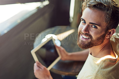 Buy stock photo Portrait of a young man using a digital tablet in a cafe