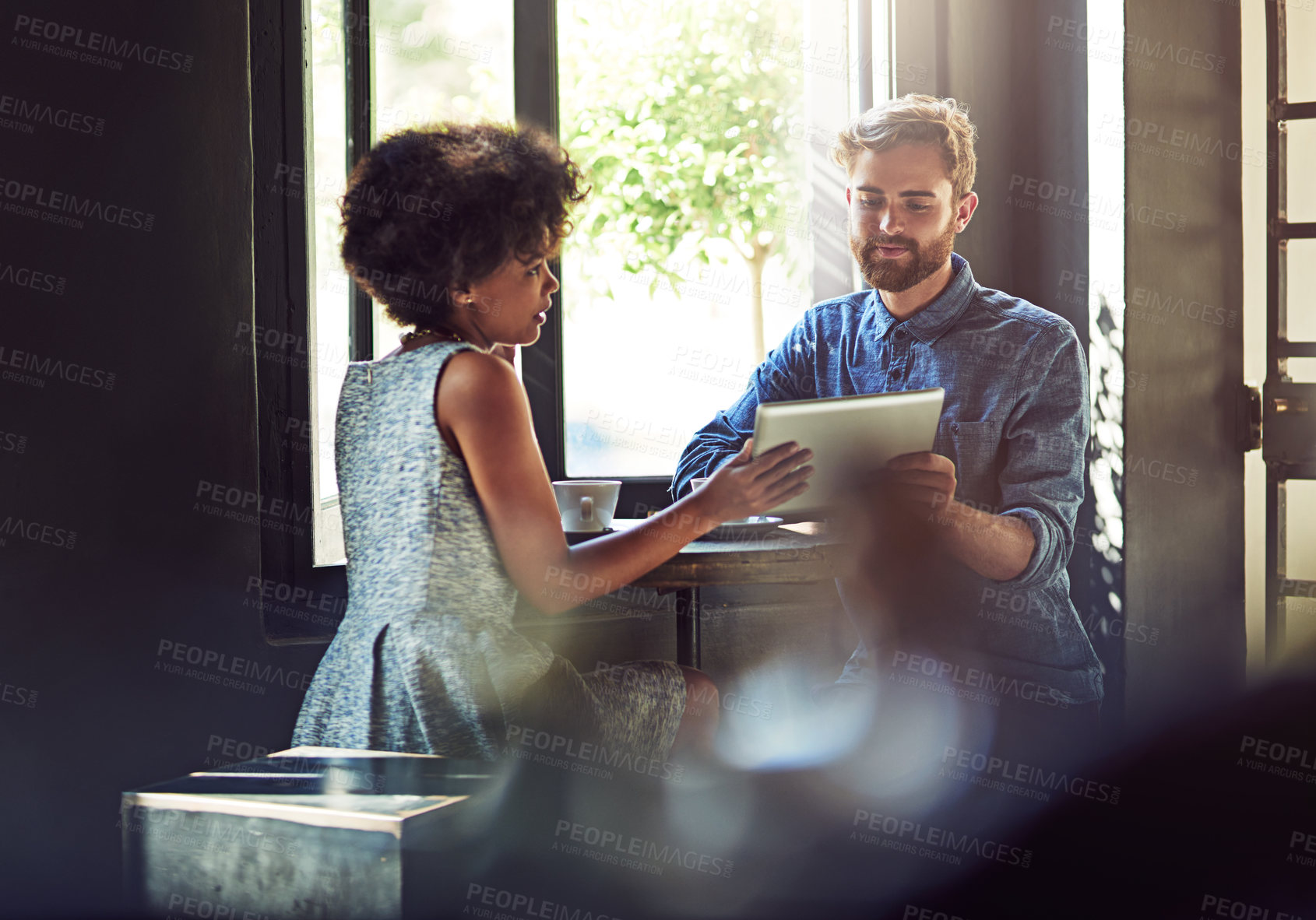 Buy stock photo Shot of two people using a digital tablet in a cafe