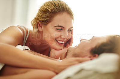 Buy stock photo Shot of an affectionate young couple relaxing in bed at home
