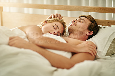 Buy stock photo Shot of a young couple asleep in bed at home