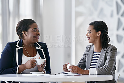 Buy stock photo Shot of two coworkers talking together while sitting at a desk in an office
