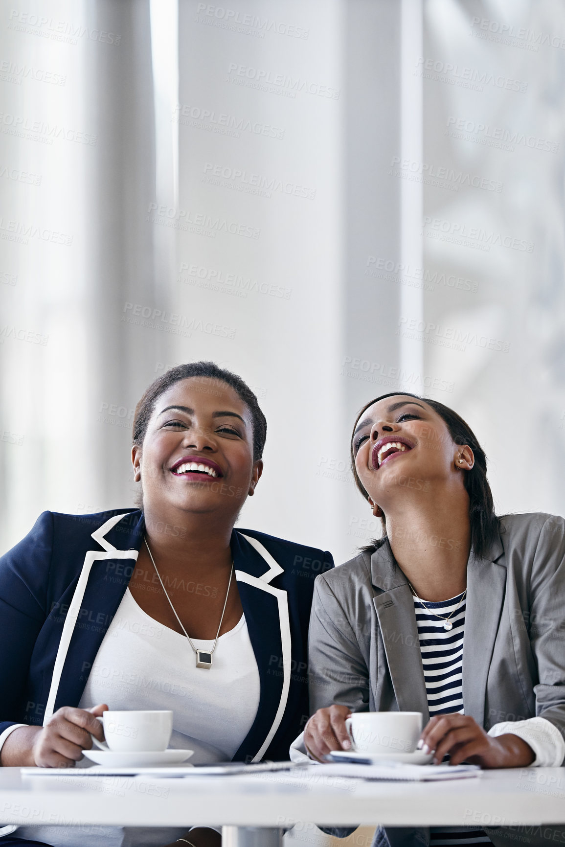 Buy stock photo Shot of two coworkers laughing together while sitting at a desk in an office