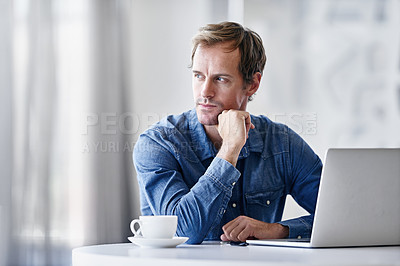 Buy stock photo Shot of a thoughtful mature businessman using a laptop while sitting at a desk in an office