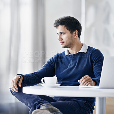 Buy stock photo Shot of a thoughtful young businessman using a laptop while sitting at a desk in an office