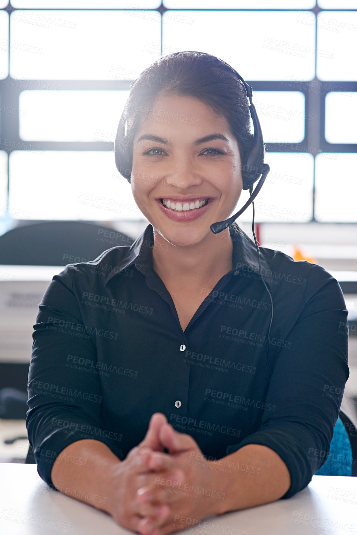 Buy stock photo Shot of a call centre agent sitting at her desk in a modern office
