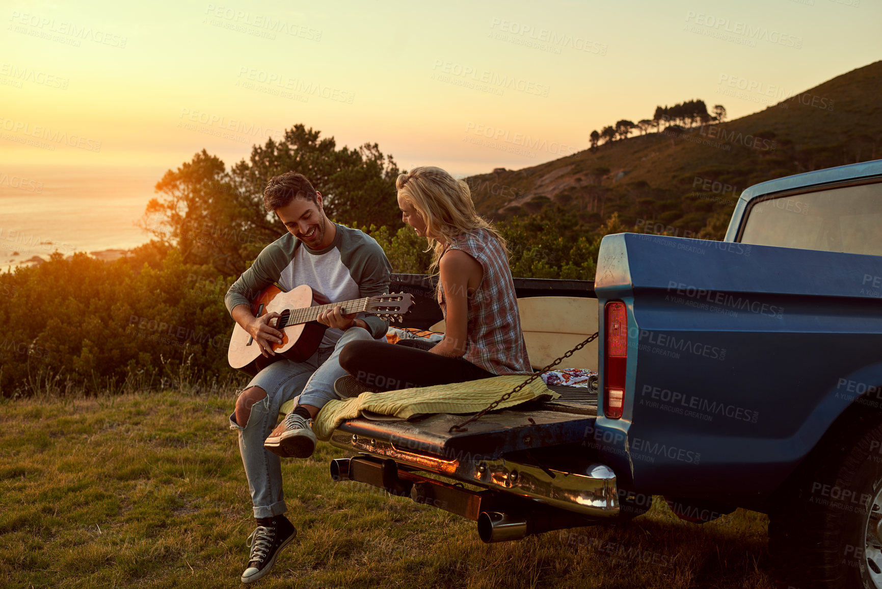 Buy stock photo Sunset, truck or couple with guitar in nature on romantic holiday vacation for bonding or relaxing on date. Car road trip, travel or people playing music in summer with romance in park field together