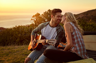 Buy stock photo Shot of a young man playing guitar for his girlfriend on a roadtrip