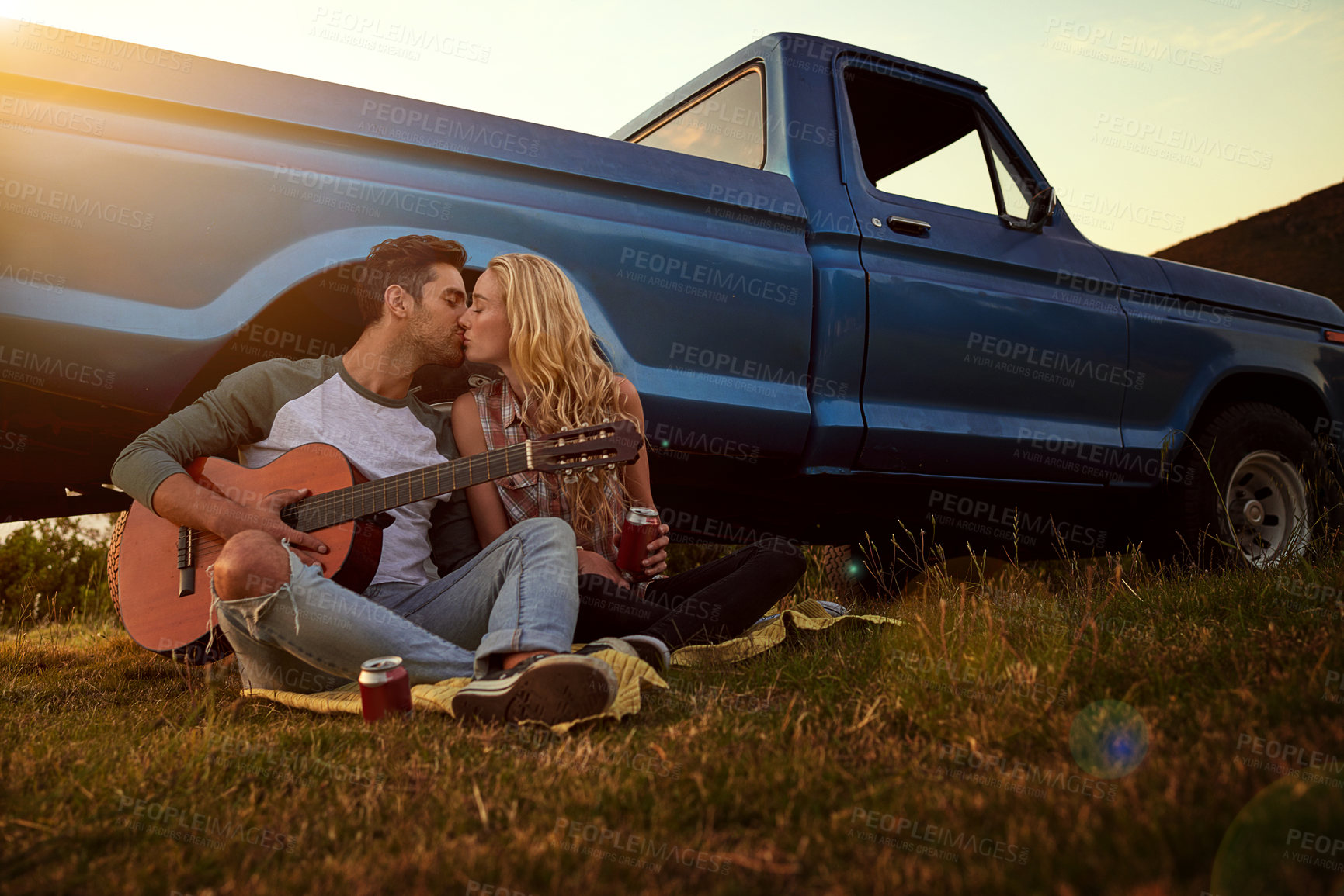 Buy stock photo Shot of a young man playing guitar for his girlfriend on a roadtrip