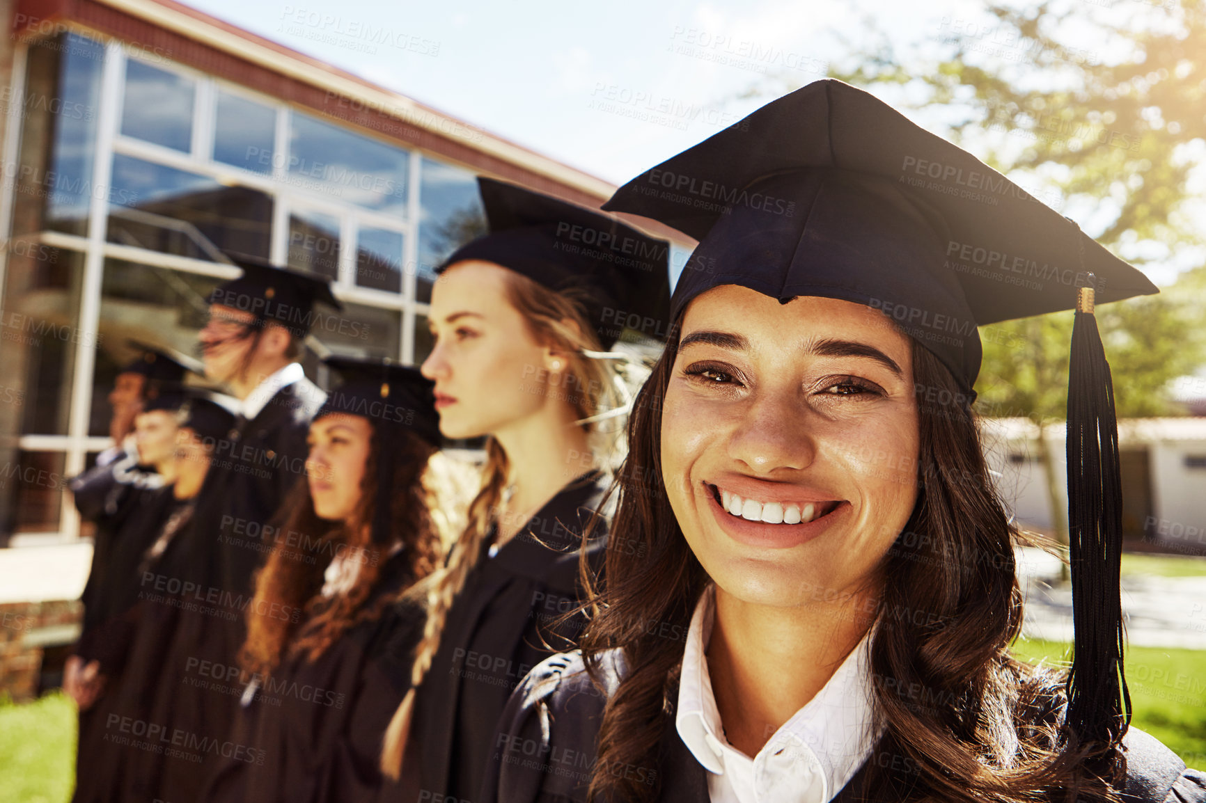 Buy stock photo Portrait of a smiling university student on graduation day with classmates in the background