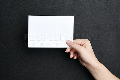 Buy stock photo Shot of a woman holding a blank board against a dark background