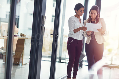 Buy stock photo Shot of businesswomen talking over some paperwork in an office